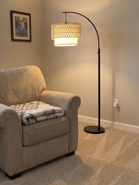 Lampadaire arqué en rotin placé près d'un fauteuil dans une vraie pièce avec DecorViz